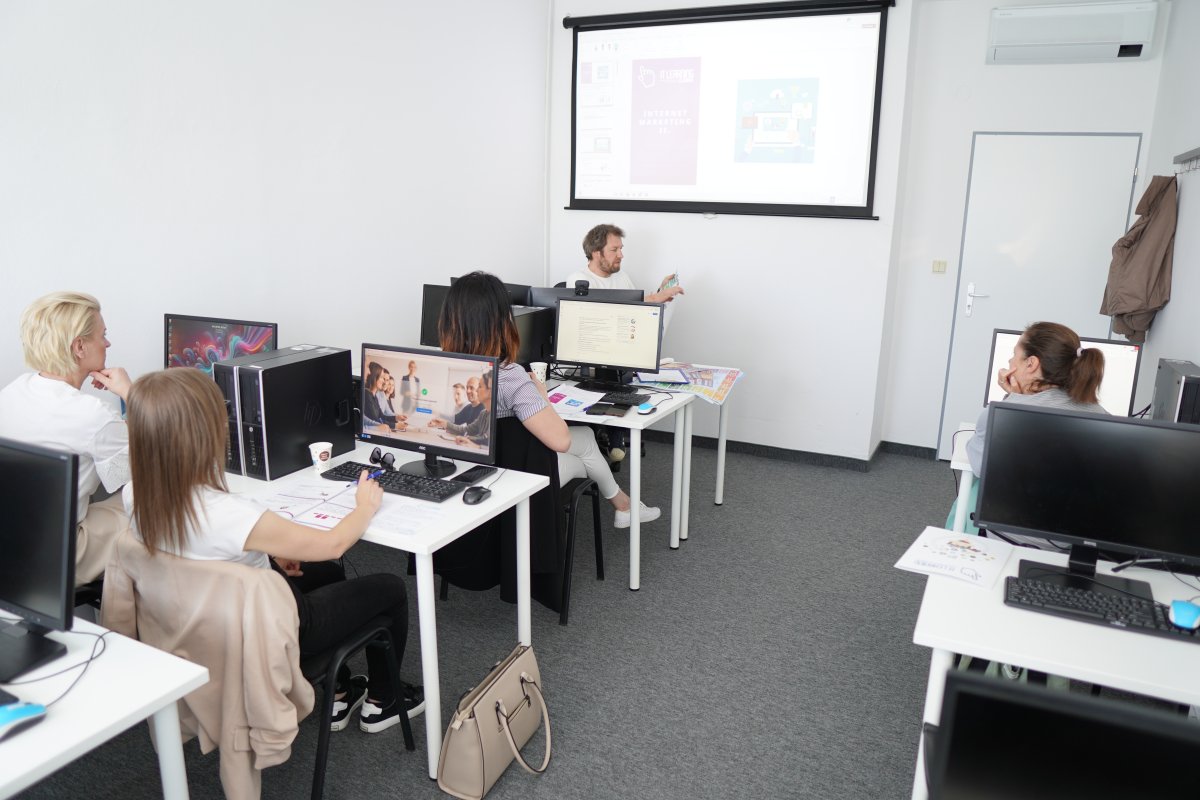 Priebeh kurzu Digitálny marketing II v učebni s projektrom na stene a účastníkmi pri počítačoch
