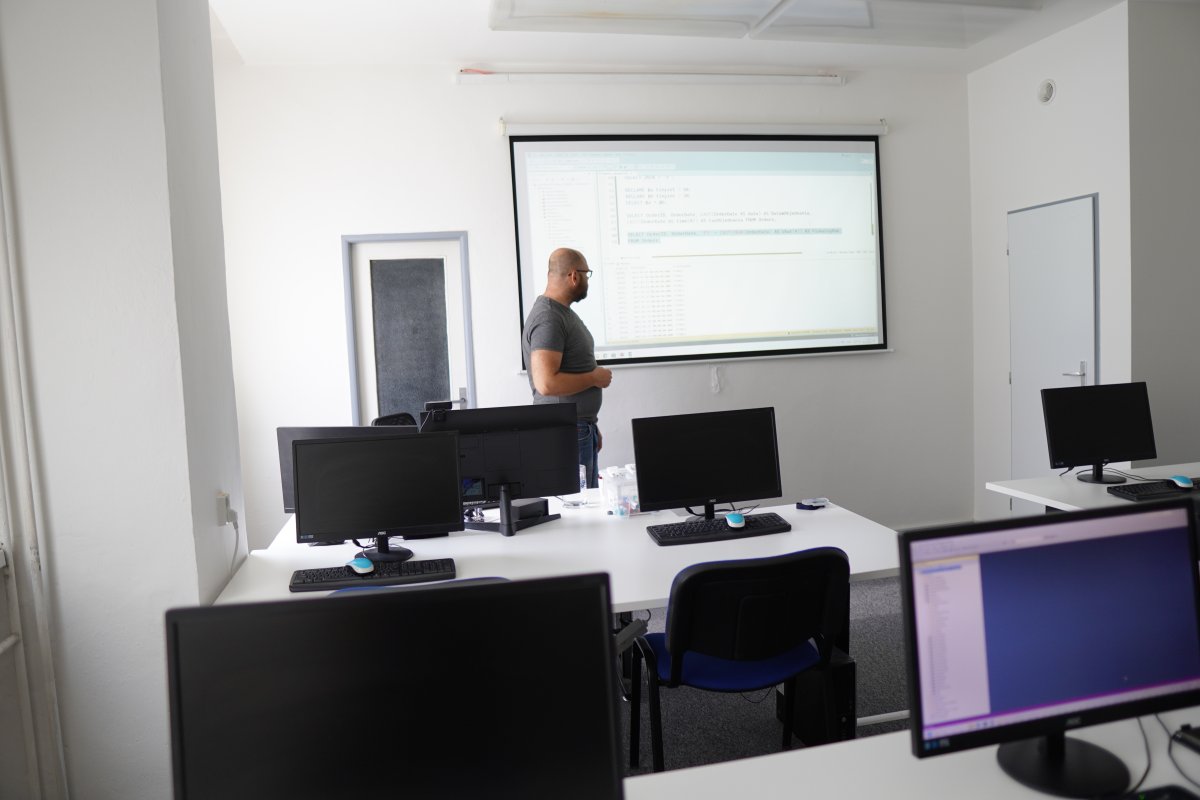 Priebeh kurzu SQL Server - učebňa s počítačmi a proyektorom s kódom