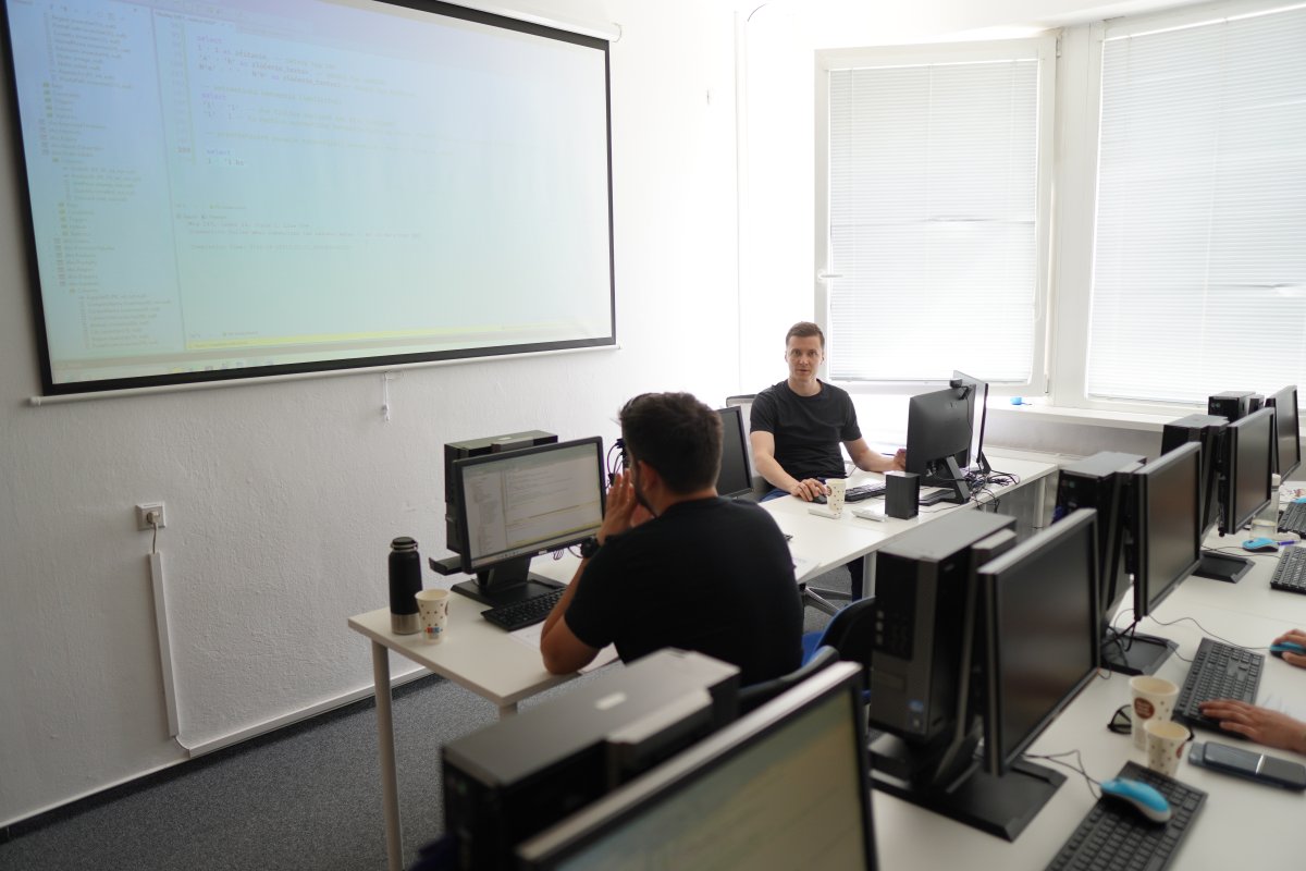 Priebeh kurzu SQL Server - počítačová učebňa s prednášajúcim pri tabuľi s kódom