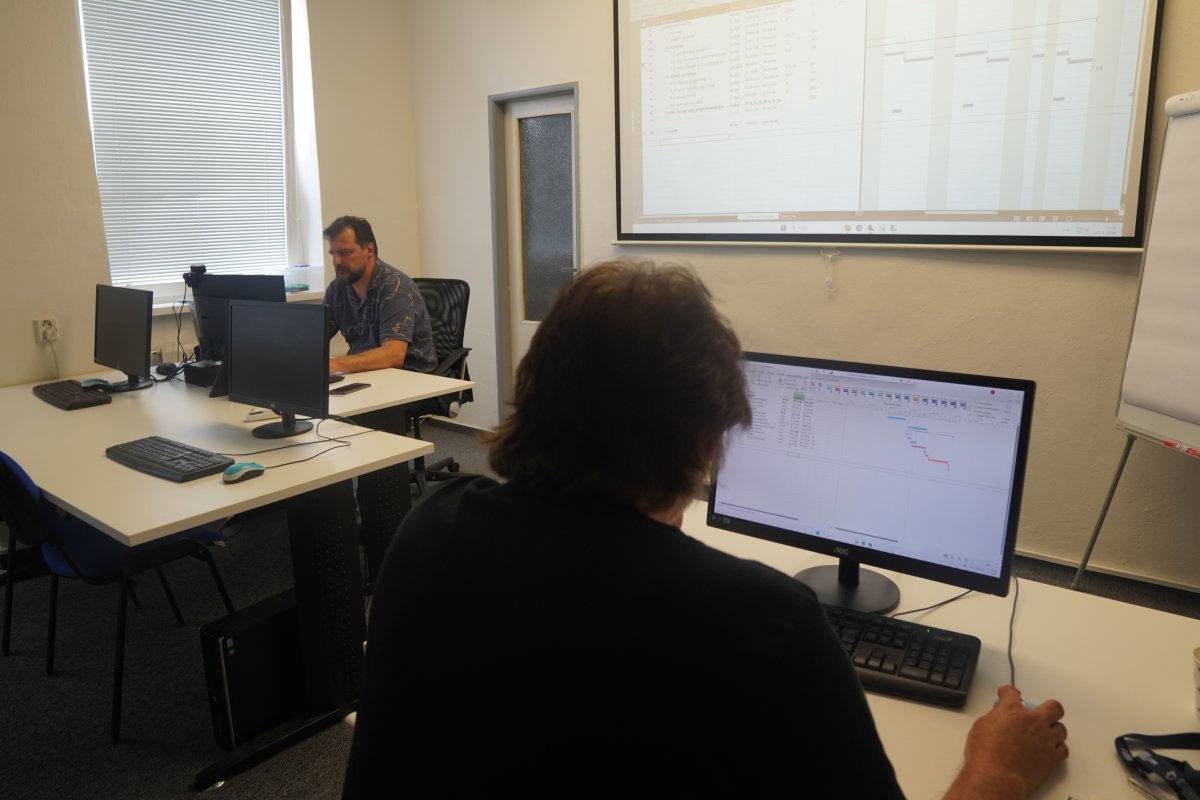 Priebeh kurzu MS Project I - učebňa s účastníkom pri počítači s Ganttovým diagramom a inštruktorom