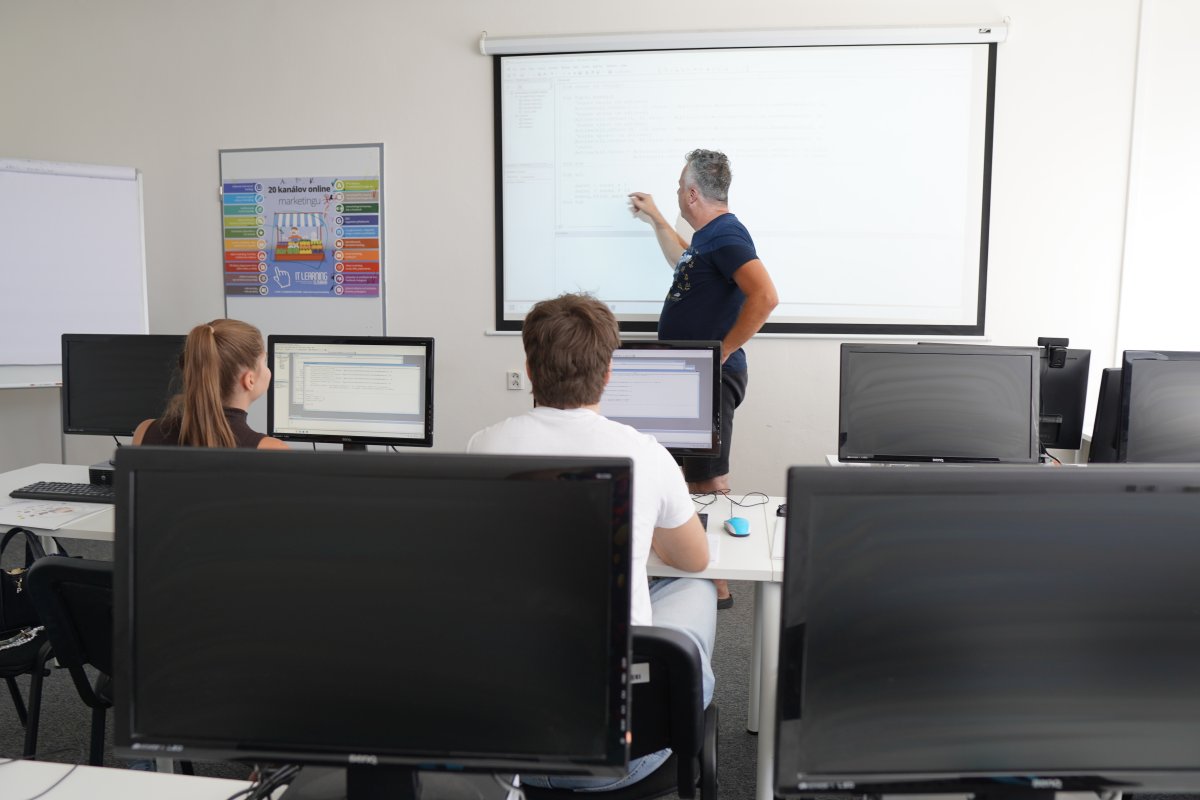 Priebeh kurzu Excel VBA II s inštruktorom pri tabuli a študentami pri počítačoch