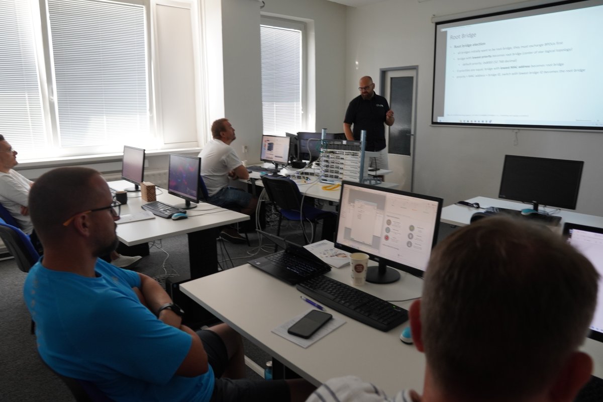 Priebeh kurzu MikroTik MTCSWE v učebni s počítačmi a projekčným plátnom s prezentáciou