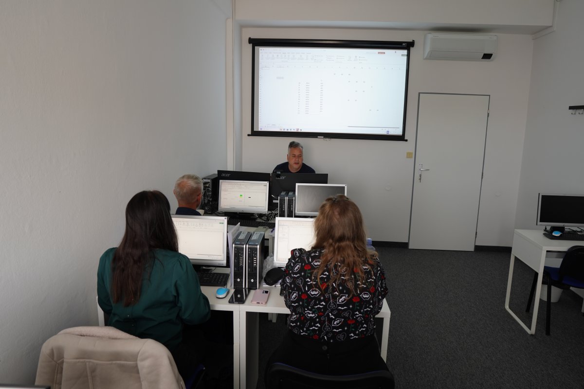 Priebeh kurzu Excel VBA I.: lektor ukazuje tabuľku v Exceli na projektore, účastníci pri počítačoch